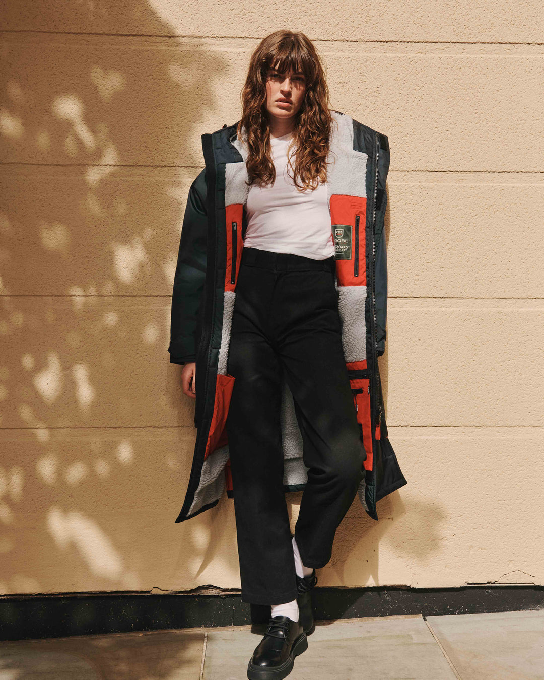 A model wearing our Anthracite Beaufort Robe which is a functional and stylish outdoor sports robe. The hooded everyday jacket for men and women is made from recycled materials, with fleece-lined, waterproof pockets, adjustable hood drawstring and velcro sleeve straps for a personalised fit.