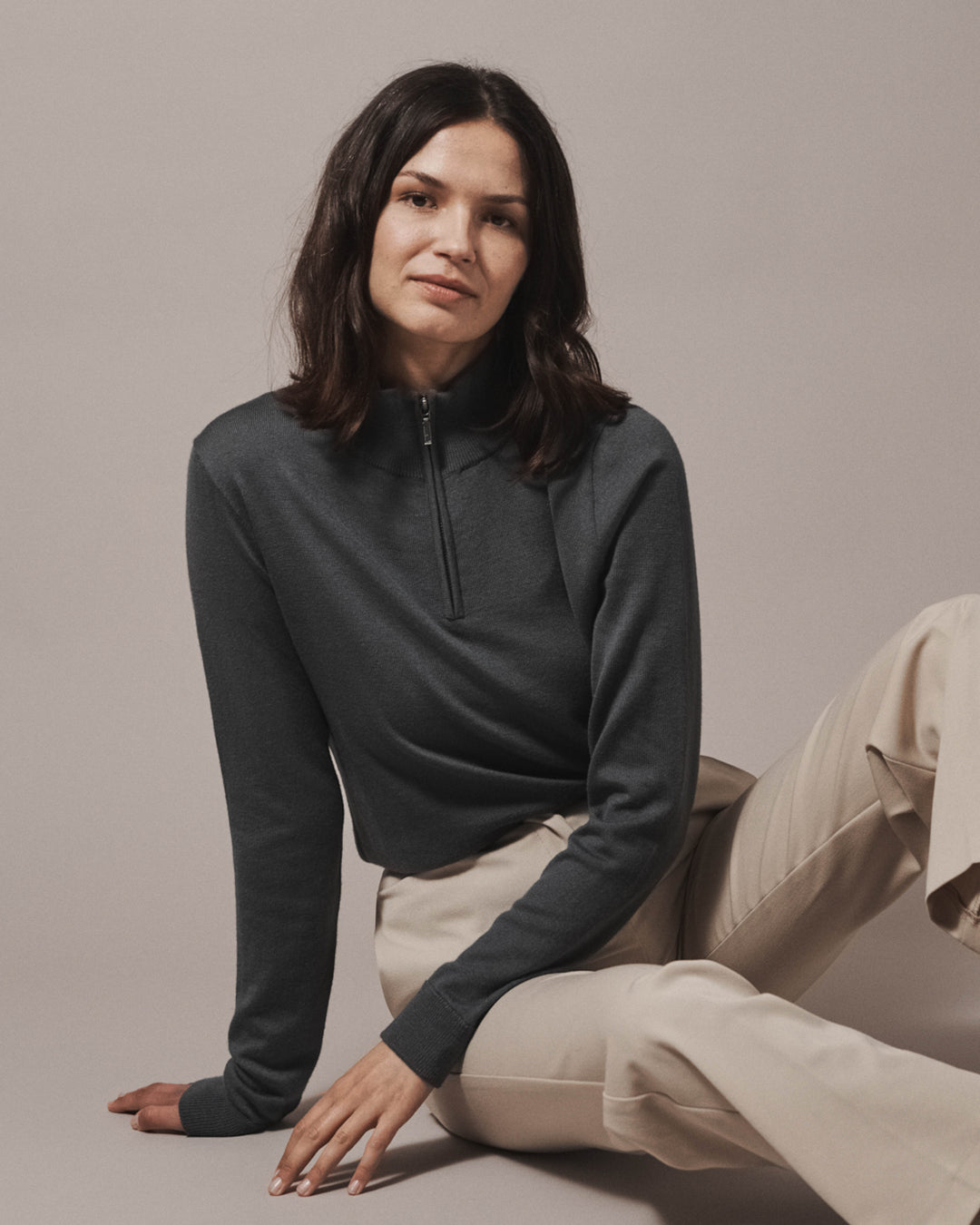 Model wearing our unisex extra-fine merino wool 1/4 zip jumper in storm grey, made from a lightweight fabric and reactive natural fibre. Ideal for layering under our waterproof dry robes for spectating touchdown sports or walking the dog. The perfect addition to any minimalist capsule wardrobe.