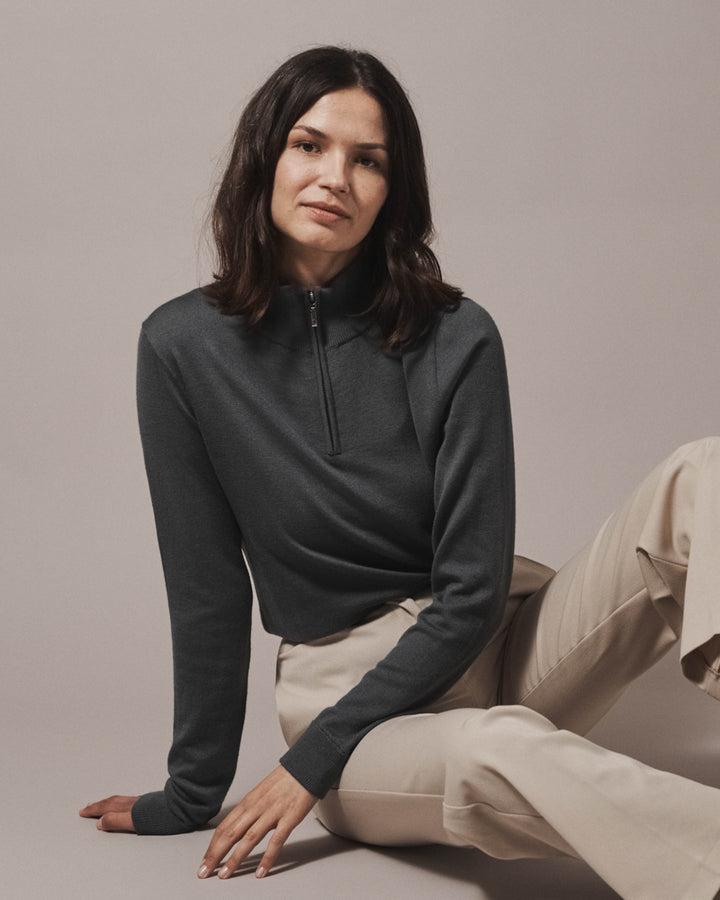 Model wearing our unisex extra-fine merino wool 1/4 zip jumper in storm grey, made from a lightweight fabric and reactive natural fibre. Ideal for layering under our waterproof dry robes for spectating touchdown sports or walking the dog. The perfect addition to any minimalist capsule wardrobe.