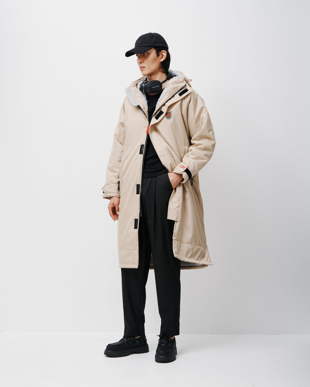 A man wearing a hooded oversized dry robe perfect for the outdoors. These hooded changing robes for men and women are made from recycled materials consisting of fleece-lined inner, waterproof pockets, and adjustable hood and cuffs. 